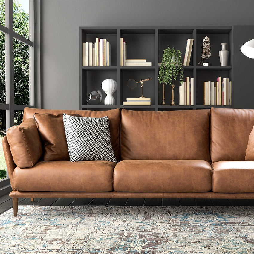 Brown leather sofa in a room with bookshelves and decorative items.