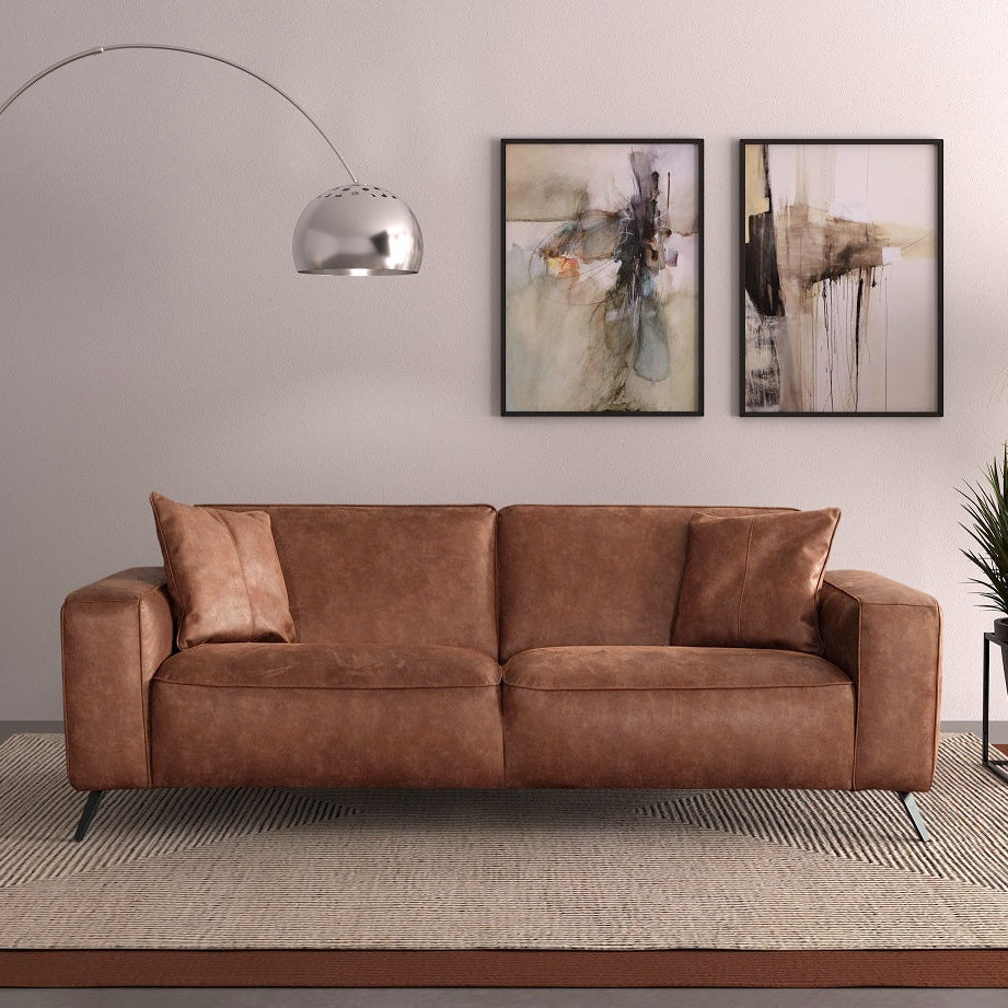 Brown leather sofa in a modern living room with abstract art and decor.
